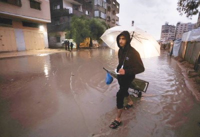 نازح يسير في شارع غمرته المياه بغزة