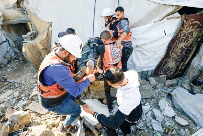 عناصر من الدفاع المدني الفلسطيني يحملون مصاباً خلال عملية بحث وإنقاذ في مخيم الشاطئ بمدينة غزة |