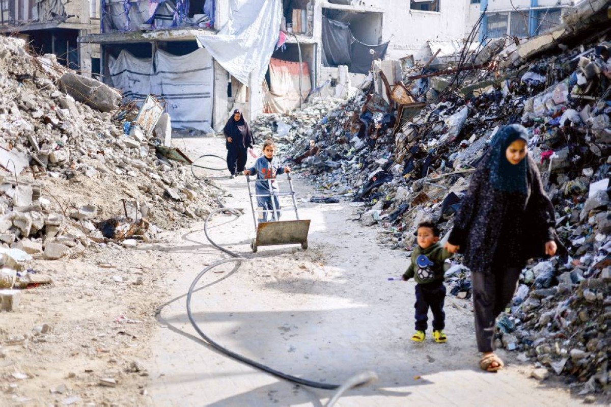 عائلة فلسطينية تعبر الطريق بين أنقاض مبانٍ سكنية دُمرت في جباليا شمال قطاع غزة