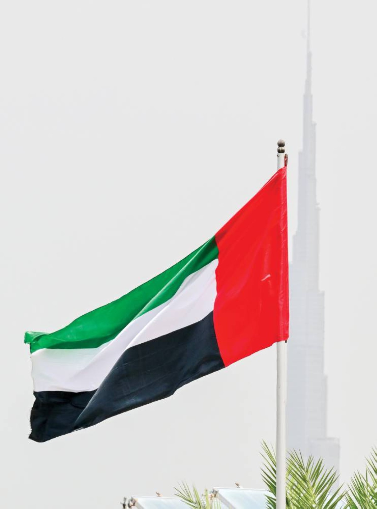 علم الإمارات ومن خلفه برج خليفة في دبي يزهو فخراً بأمجاد الإمارات 