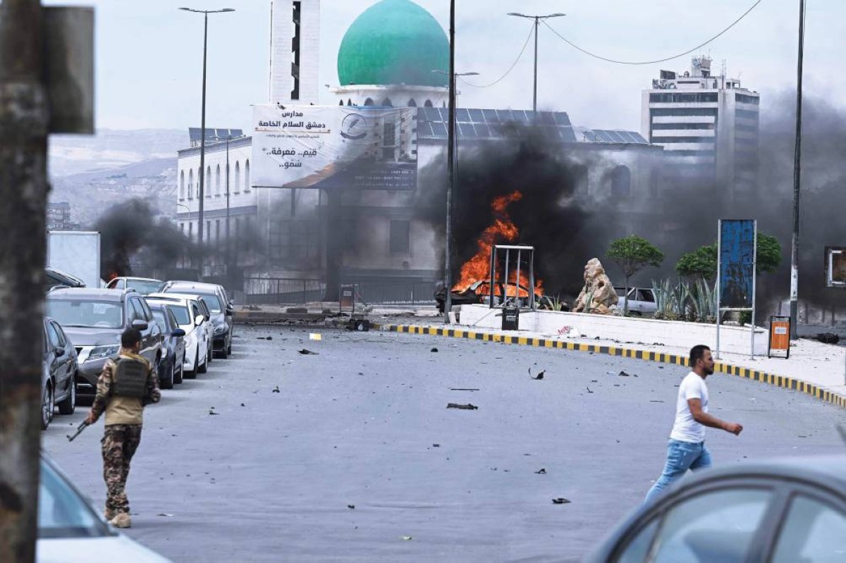 عنصر أمن قرب سيارة محترقة في موقع الانفجار في دمشق