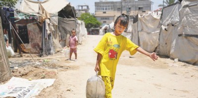 طفلة فلسطينية نازحة تحمل عبوة مياه مملوءة في دير البلح وسط غزة