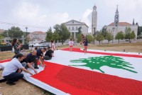 لبنانيون يصنعون علم بلادهم من أغطية وزجاجات فارغة في قرية عجلتون شمال بيروت