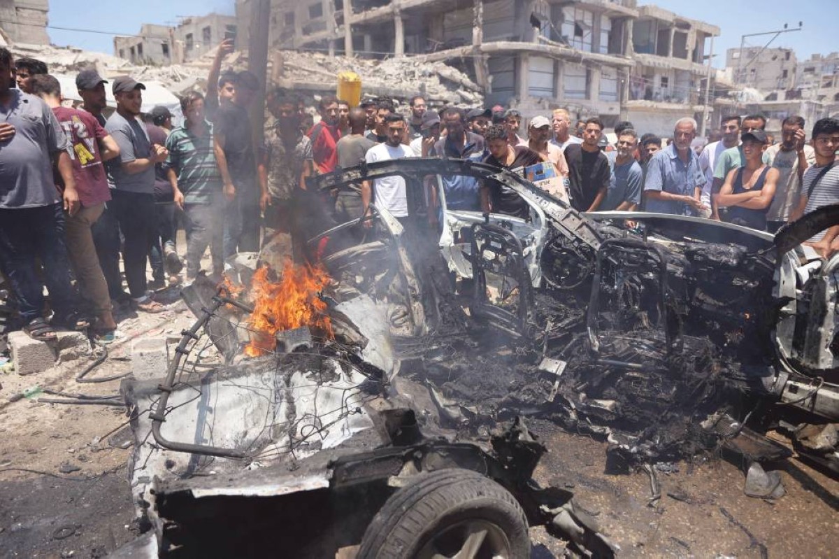 فلسطينيون نازحون يتجمعون حول مركبة مدمرة في موقع غارة إسرائيلية بمدينة غزة