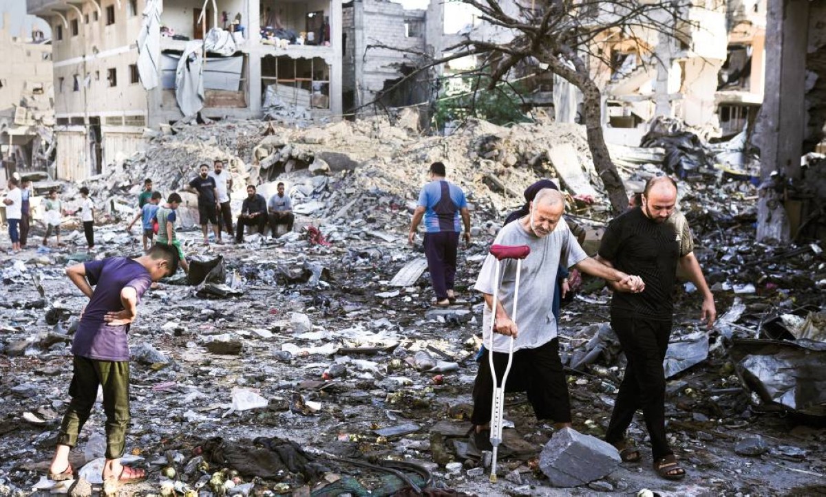 فلسطينيون أمام أنقاض مبنى دمره قصف إسرائيلي في غزة