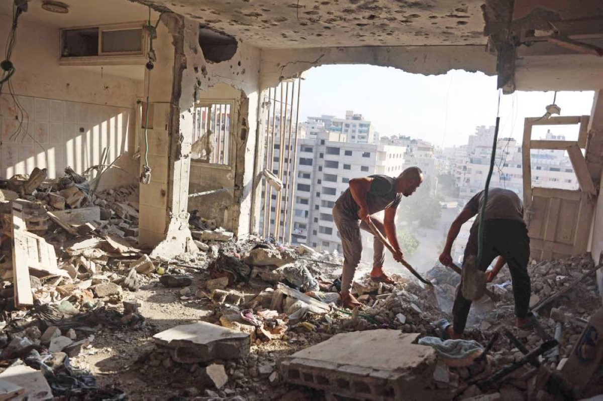 فلسطينيان يبحثان عن أحياء تحت أنقاض مبنى دمرته غارة إسرائيلية في مدينة غزة