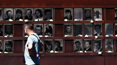 زائر أمام صور لأشخاص حاولوا الفرار من ألمانيا الشرقية خلال معرض لإحياء الذكرى 65 لبناء جدار برلين
