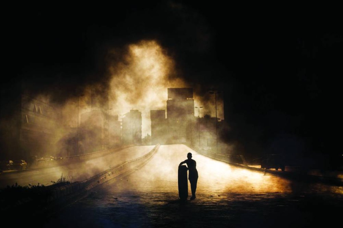 Beirut, Lebanon. October 18th, 2019. The beggining of the revolution. First day. A protester throws a tyre on to a fire to block a road during a protest in north of Beirut, Lebanon Lebanon. Diego Ibarra Sánchez for The New York Times