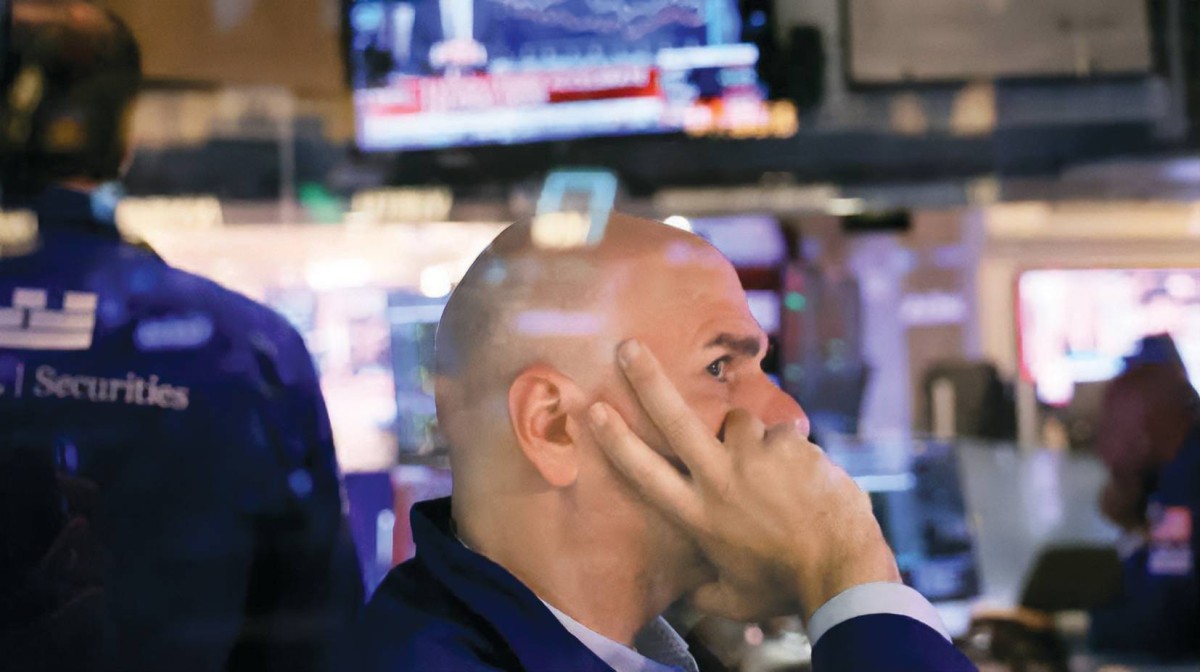 مستثمر يتابع حركة مؤشرات «وول ستريت» بقلق