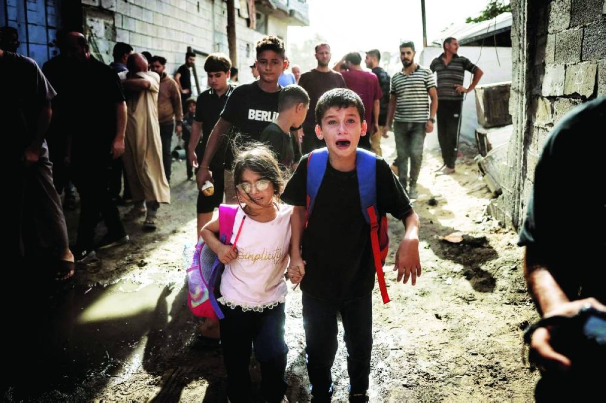 أطفال فلسطينيون يبكون أثناء فرارهم من موقع غارة إسرائيلية في جباليا، شمالي قطاع غزة / أ.ف.ب