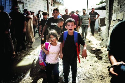 أطفال فلسطينيون يبكون أثناء فرارهم من موقع غارة إسرائيلية في جباليا، شمالي قطاع غزة / أ.ف.ب