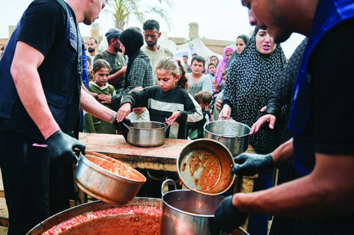 فلسطينيون يتسلمون وجبات غذائية من برنامج الأغذية العالمي في مخيم للنازحين في دير البلح | أ.ب