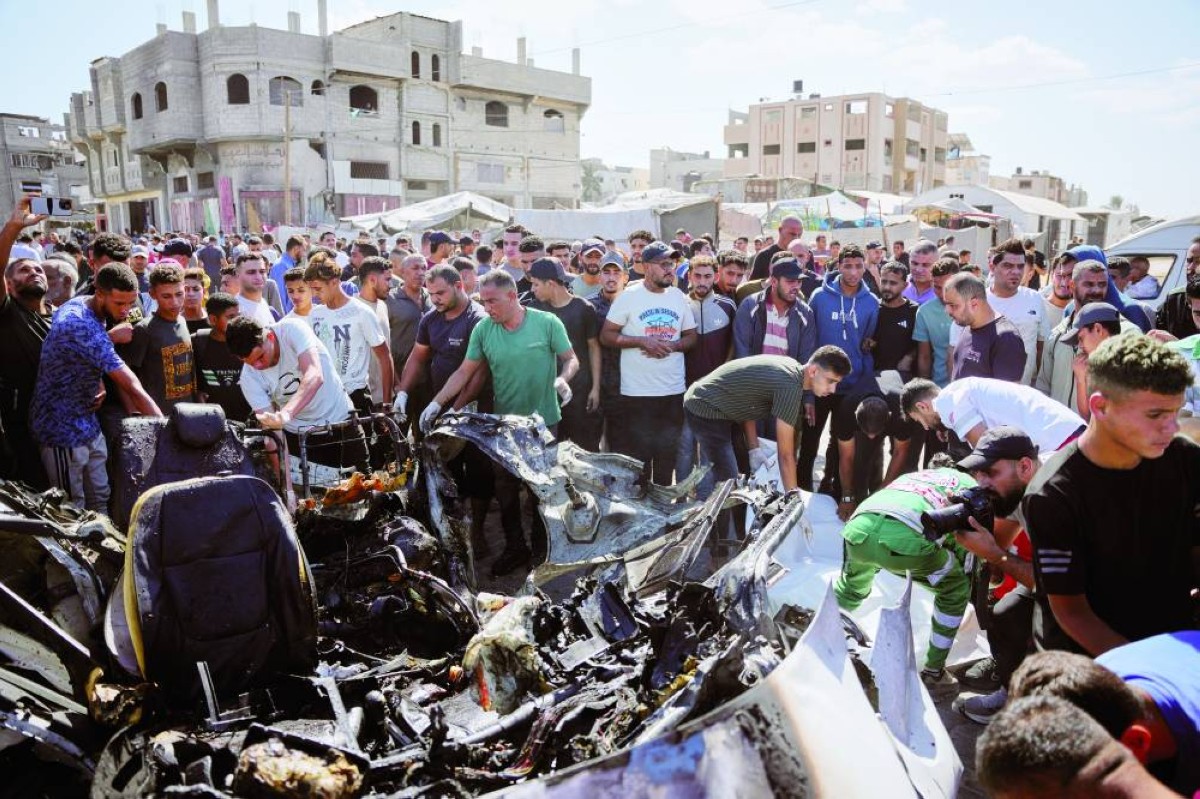 فلسطينيون يتفقدون حطام مركبة استهدفتها غارة إسرائيلية في مخيم المغازي للاجئين وسط قطاع غزة / أ.ب