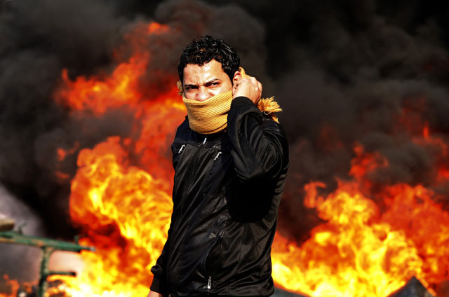 الصورة: متظاهر يقف أمام حاجز محترق خلال التظاهرات في القاهرة