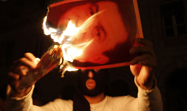 الصورة: متظاهر يحرق صورة الرئيس حسني مبارك خلال الإشتباكات في مصر