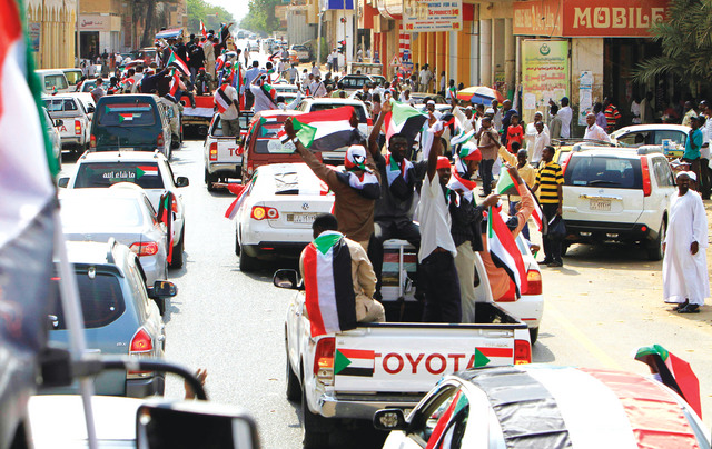الصورة : سودانيون يرفعون علم بلادهم في شوارع الخرطوم (أ.ف.ب)