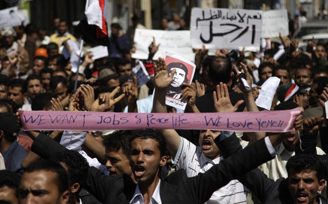الصورة: محتجين مناهضين للحكومة يحملون لافتة خلال مظاهرة أمام القصر الرئاسي في صنعاء