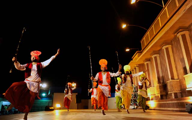 الصورة: عدد من العارضين بالزي الشعبي الهندي يقدمون لوحة موسيقية لجمهور القرية العالمية