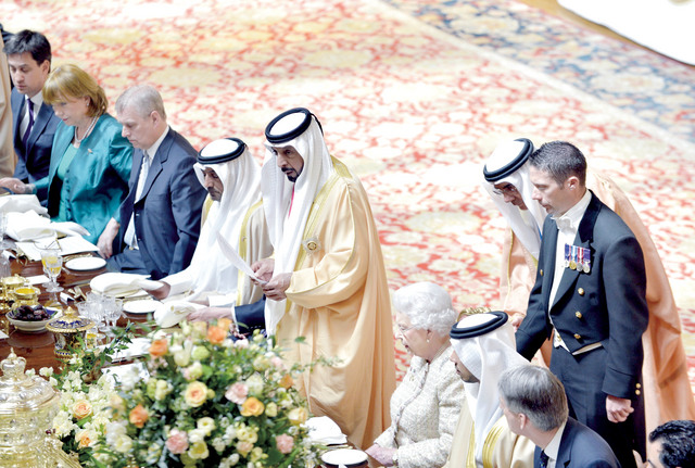 الصورة : رئيس الدولة متحدثاً خلال المأدبة وإلى جواره الملكة إليزابيث ومنصور بن زايد وأحمد بن سعيد