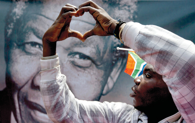 الصورة : مواطن جنوب أفريقي يشكل قلباً بيديه أمام ملصق لمانديلا في بريتورياأ.ب
