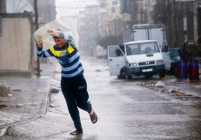 الصورة : فلسطيني يحتمي من الأمطار بكيس بلاستيكي بمخيم الشاطئ في غزةرويترز
