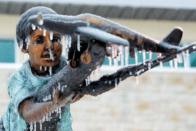 الصورة : تمثال برونزي في باحة مطار ولاية تكساس الأميركية مغطى بالثلوج التي هطلت بكثافة فوق مناطق الولاية إي.بي.إيه
