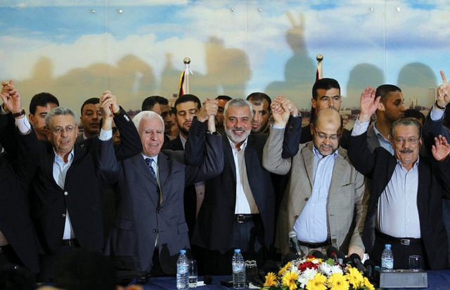 الصورة : أعضاء وفدي منظمة التحرير وحركة حماس يشبكون الأيادي بعد توقيع اتفاق المصالحة	أ.ف.ب