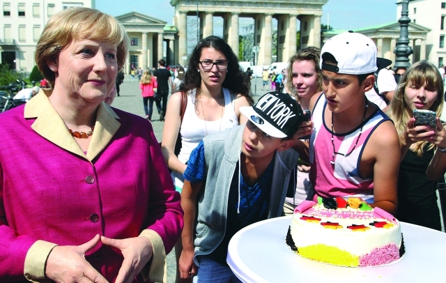 الصورة : زائرون يلتقطون صوراً لهم مع تمثال نصب وسط برلين احتفالاً بميلادها	رويترز