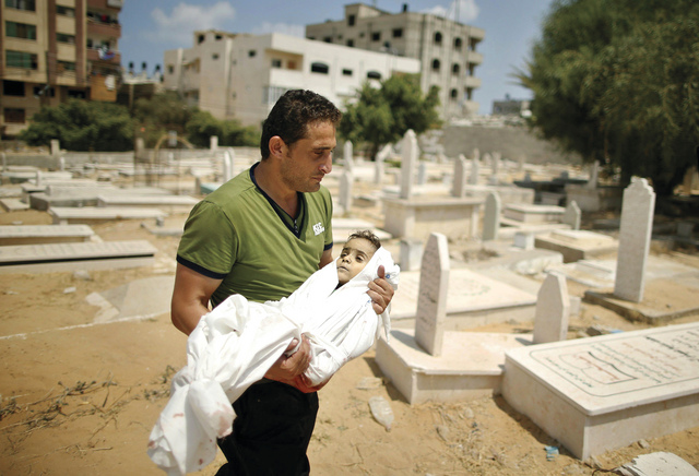 الصورة : خال الطفل الشهيد محمد عياد يحمله إلى المقبرة في مدينة غزة 	رويترز