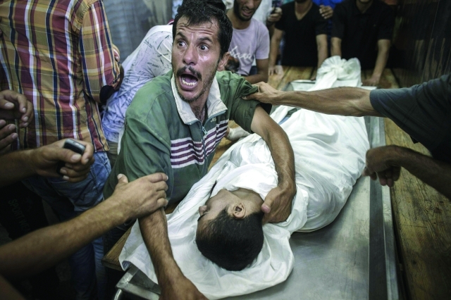 الصورة : أب فلسطيني يبكي ابنه الذي استشهد بقصف مدرسة  «الأونروا» اي.بي.ايه