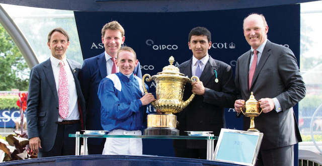 الصورة : راشد بن عبد العزيز يحمل كأس الفوز مع الفارس  هاناغان وبجانبه المدرب  جون جوسدن