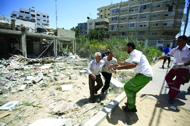 الصورة : مسعفون يحاولون مساعدة أحد الناجين من القصف              أ.ف.ب