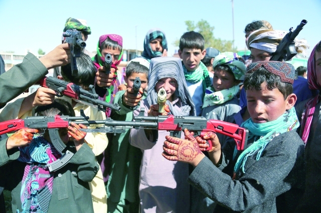 الصورة : أطفال أفغان يحتفلون في إقليم غيزني باللعب ببنادق بلاستيكية بأيديهم الصغيرة التي تغطيها الحناء	أ.ف.ب