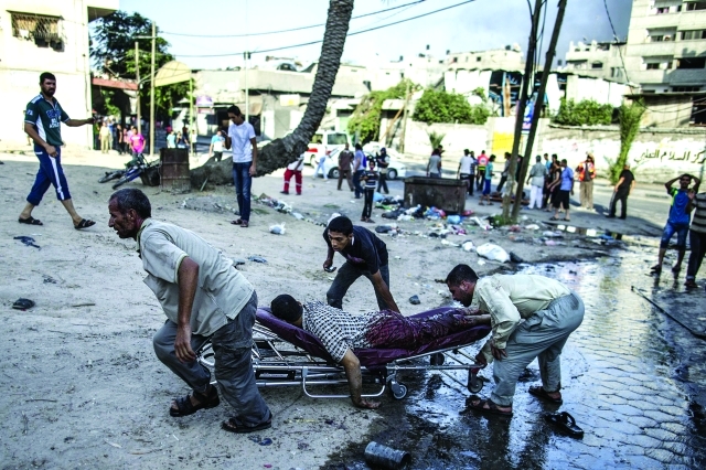 الصورة : فلسطينيون يحملون شهيداً سقط في غارة على الشجاعية                         أ.ف.ب