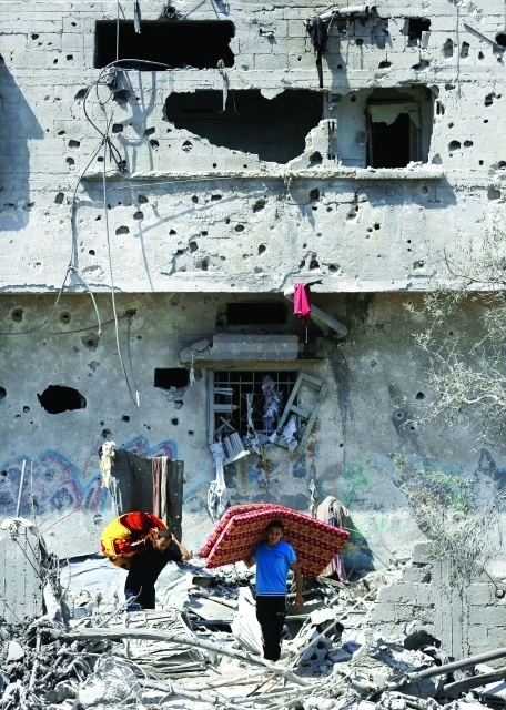 الصورة : فلسطينيان يحملان بقايا أثاث منزلهما بعد قصفه في حي الشجاعية     أ.ف.ب