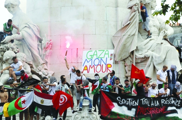 الصورة : متظاهرون يتسلقون نصباً تذكارياً في باريس خلال مواجهات مع قوات الأمن التي تصدت لاحتجاج ضد الحرب على غزة أ.ف.ب