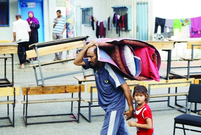 الصورة : لاجئ فلسطيني مع طفلته في أحد مدارس «الأونروا» في مخيم جباليا شمال القطاع أ.ف.ب
