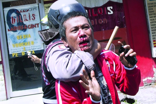 الصورة : شرطي أندونيسي يعتقل أحد المصابين خلال تظاهرات في منطقة الضوء الأحمر سوابايا عشية عيد الفطر أ.ف.ب