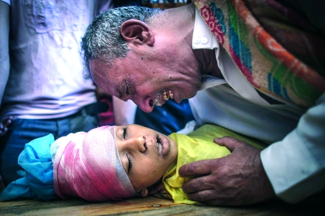 الصورة : أب يبكي على  طفله الذي استشهد في غارة إسرائيلية 		إي.بي.إيه