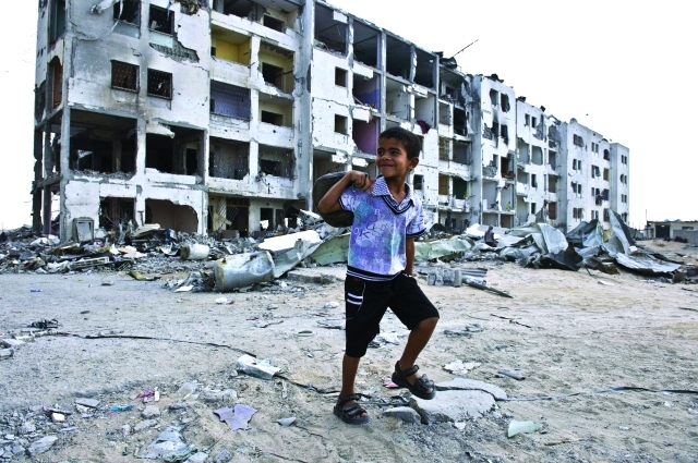 الصورة : طفل يبتسم بالقرب من مبان مدمرة في بيت حانون      أ.ف.ب