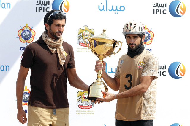 الصورة : حمدان بن محمد يتسلم  من ناصر بن حمد كأس بطولة  العالم  العسكرية  للقدرة