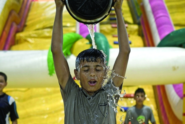 الصورة : ■ طفل فلسطيني يصب دلو ماء على رأسه جراء الحرارة  |  أ.ف.ب