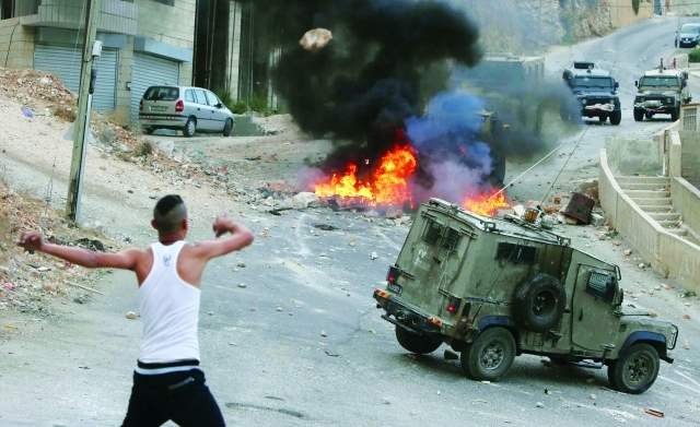 الصورة : ■ فتى فلسطيني يهاجم سيارة عسكرية للاحتلال في نابلس  |   أ.ف.ب