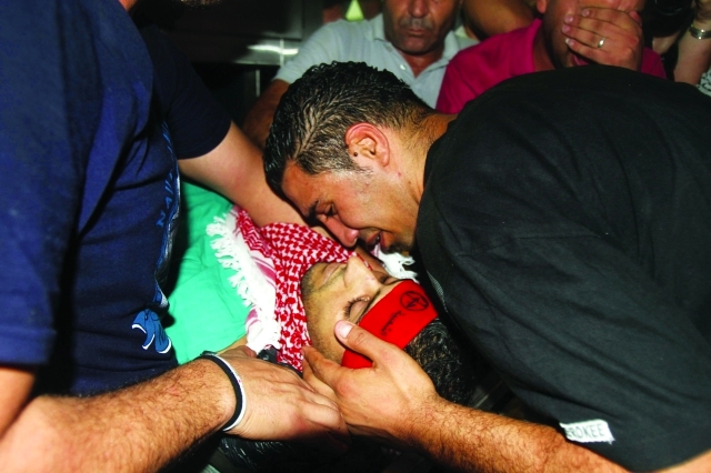 الصورة : ■ أحد أقارب الشهيد معتز زواهرة يقبّله في المستشفى ببيت لحم  |  أ.ف.ب