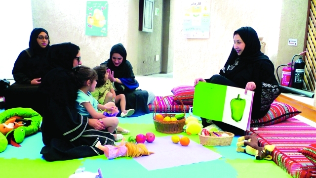 الصورة : الأمهات والصغار يستمعون إلى حكايات وقصص من سفيرة القراءة حنان عيد  |  البيان