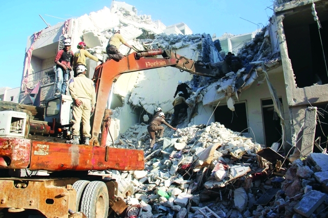 الصورة : متطوعون في الدفاع المدني يستخدمون إحدى الآليات للوصول إلى المبنى الذي دمره القصف في ادلب أ.ف.ب