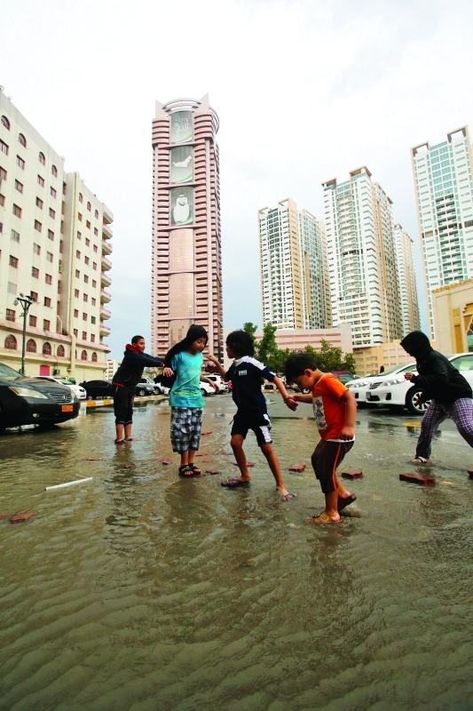 الصورة : أطفال يستمتعون بأجواء المطر في عجمان