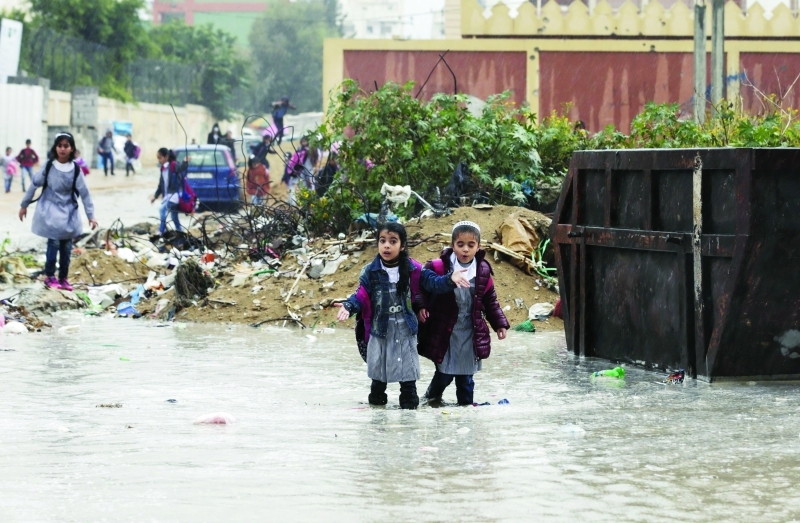 الصورة : تلميذتان تسيران وسط شارع غمرته المياه في غزة  |  أ.ف.ب