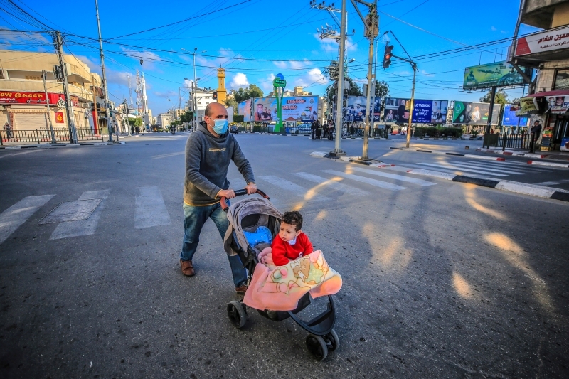 الصورة : يدفع عربة طفله في أحد شوارع غزة | إي.بي.إيه