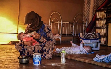 الصورة: الصورة: أم تاج تخشى على توأمها من البرد في مخيمات سوريا